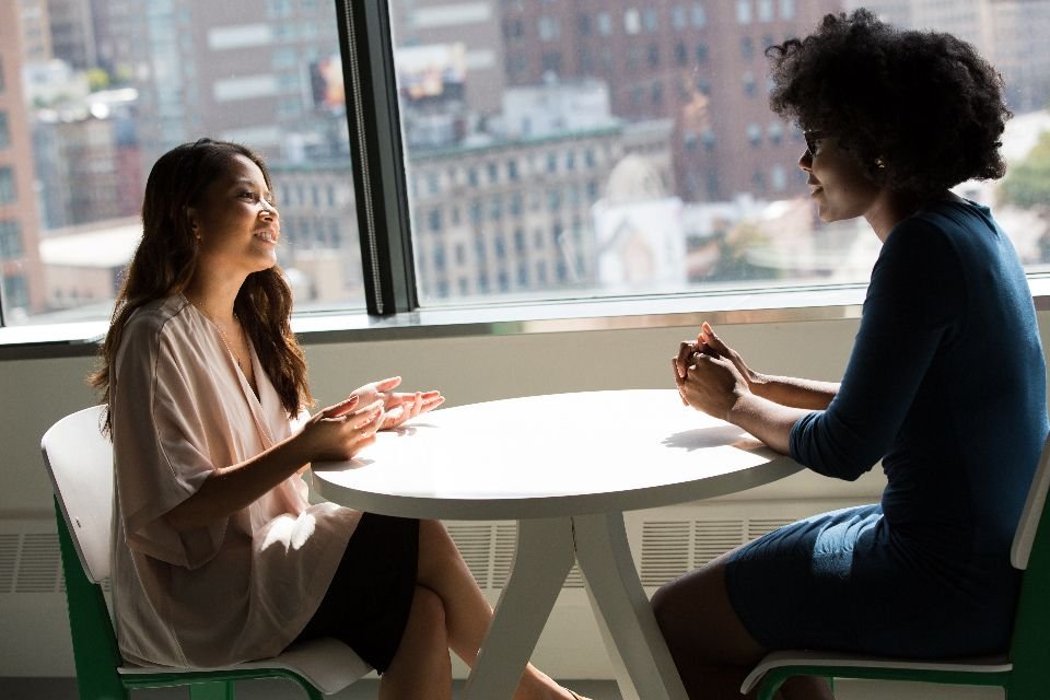 Duas profissionais conversando em uma mesa de reunião